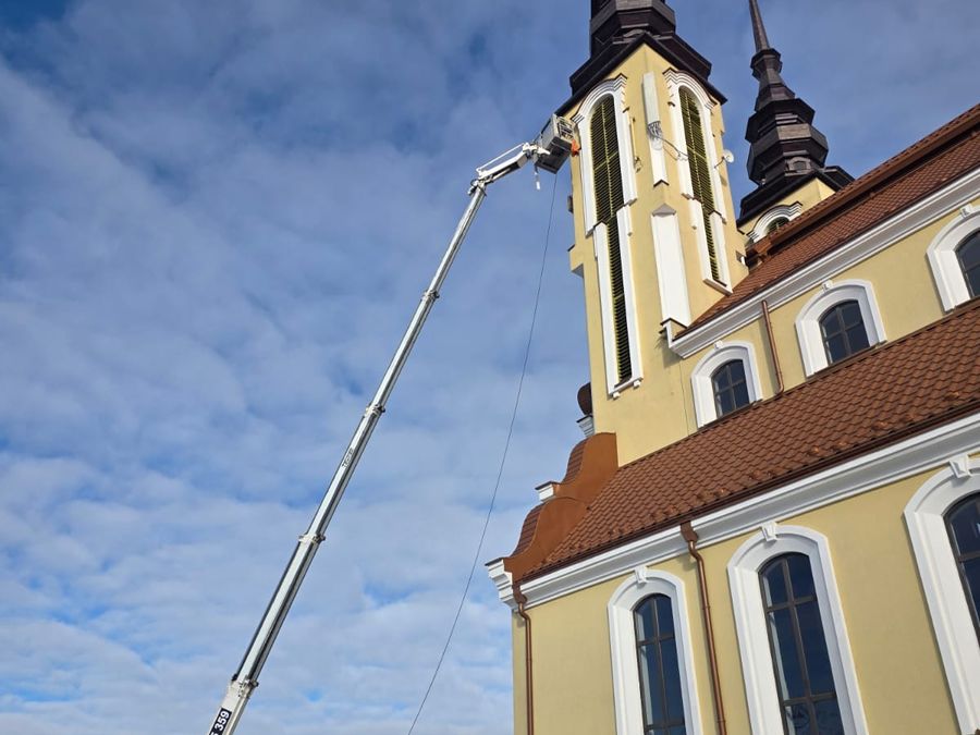 Podnośnik koszowy z wysięgnikiem przy wieży kościoła podczas prac na wysokości